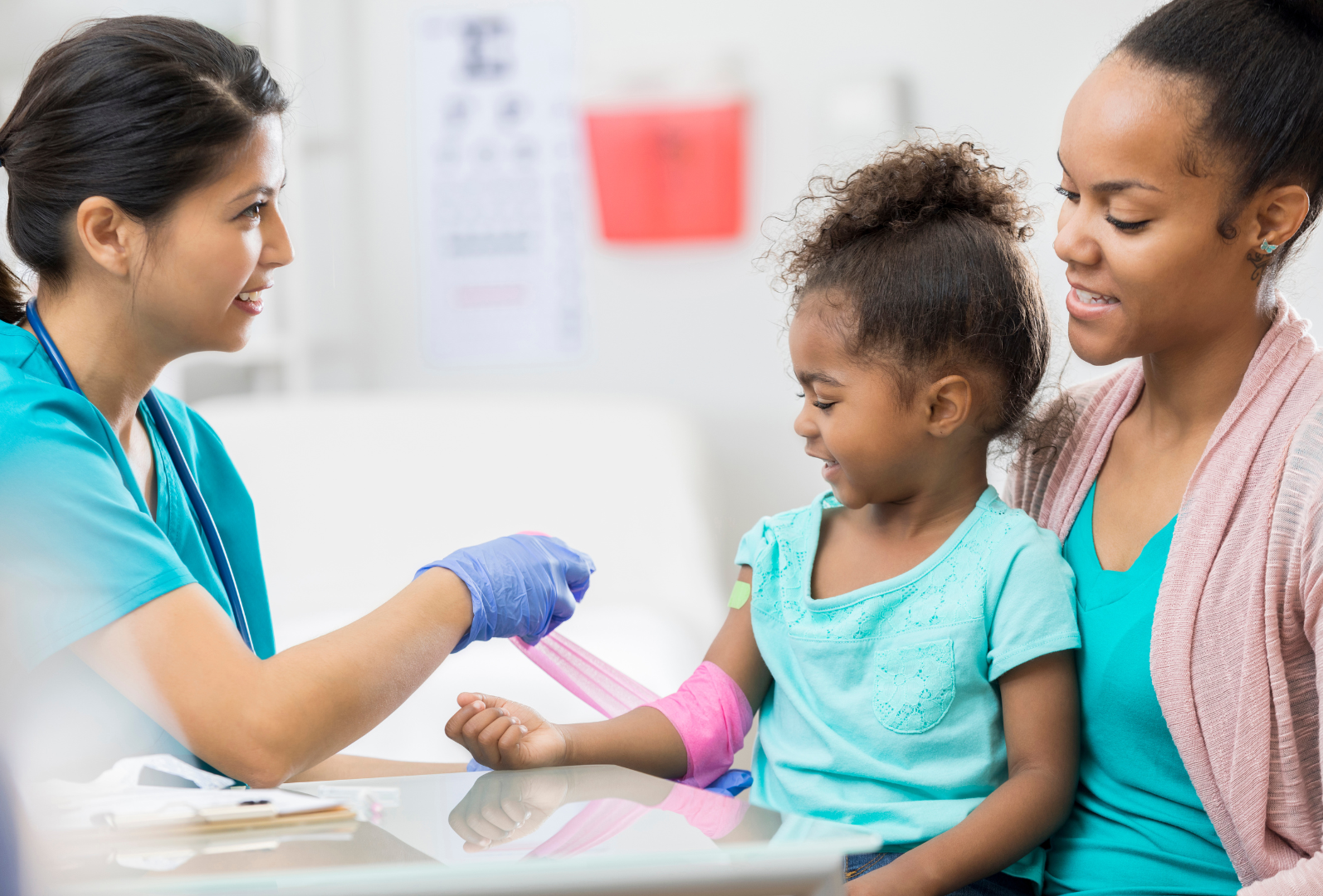 Nurse practitioner bandaging child's arm in clinic with mom present