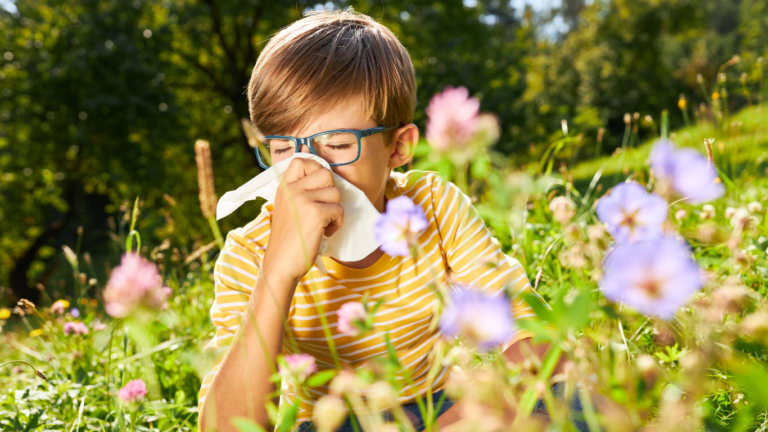 Pre-teen in flower garden with a tissue, showing allergy symptoms